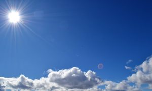 A blue sky with clouds and the sun.