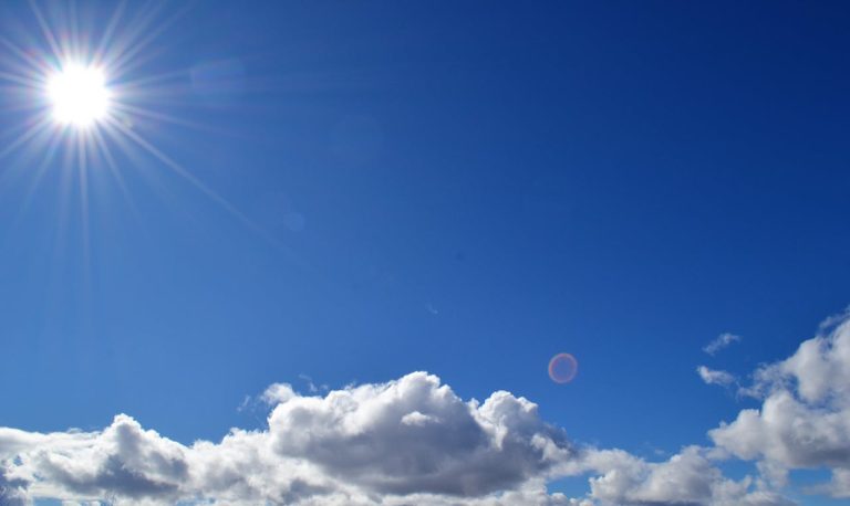 A blue sky with clouds and the sun.